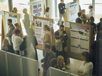 Menschen diskutieren angeregt vor mehreren wissenschaftlichen Postern bei einer Tagung der Allianz für Lehrkräftebildung im Wissenschaftszentrum in Kiel. Es ist ein heller Raum mit großen Fenstern. Die Poster sind auf Stellwänden angebracht und zeigen Texte, Diagramme und Bilder. Die Teilnehmer*innen stehen in kleinen Gruppen zusammen, lesen die Poster oder unterhalten sich miteinander.